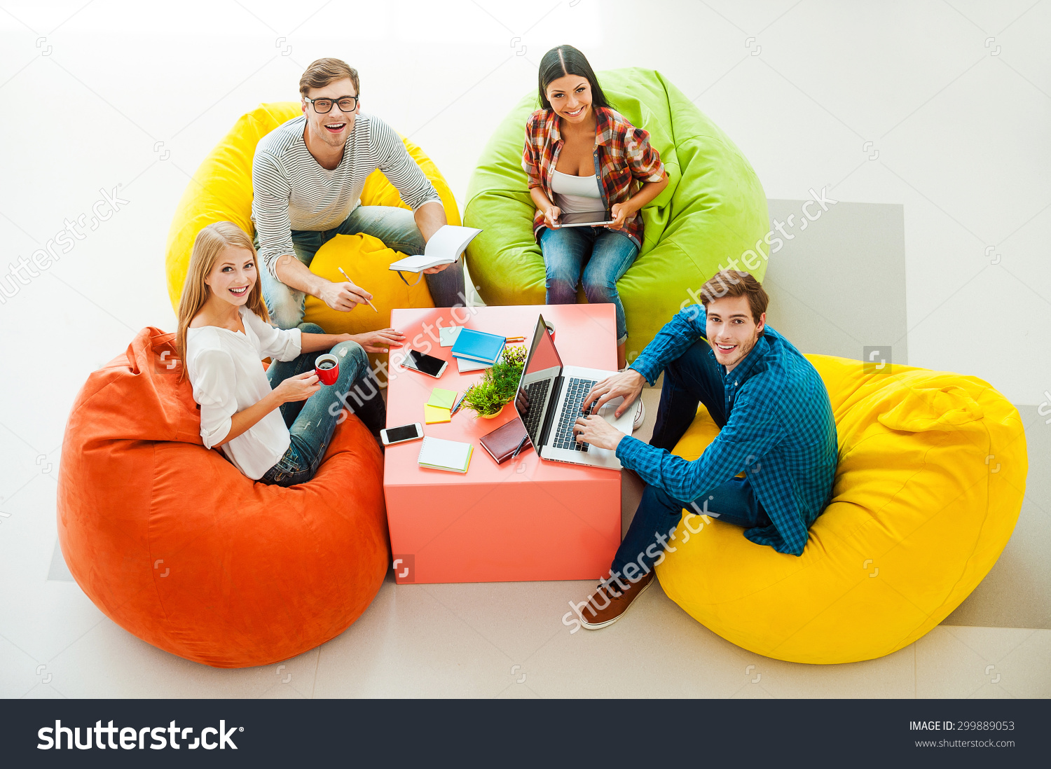 stock-photo-creative-work-space-top-view-of-four-cheerful-young-people-working-together-and-looking-up-while-299889053-1